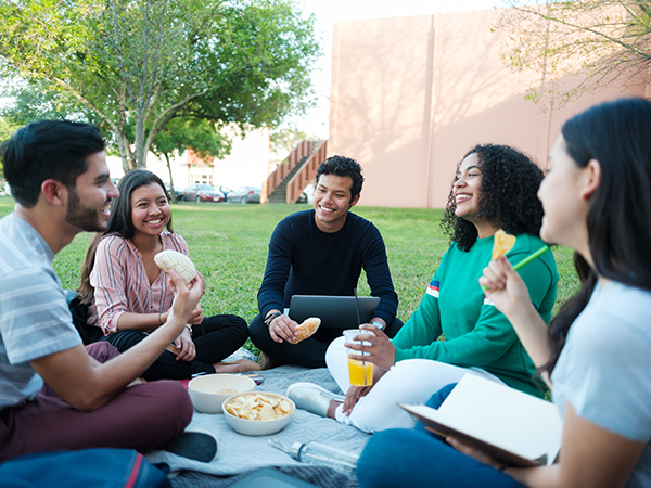 Cheerful college students meeting outside to study while eating snacks.
